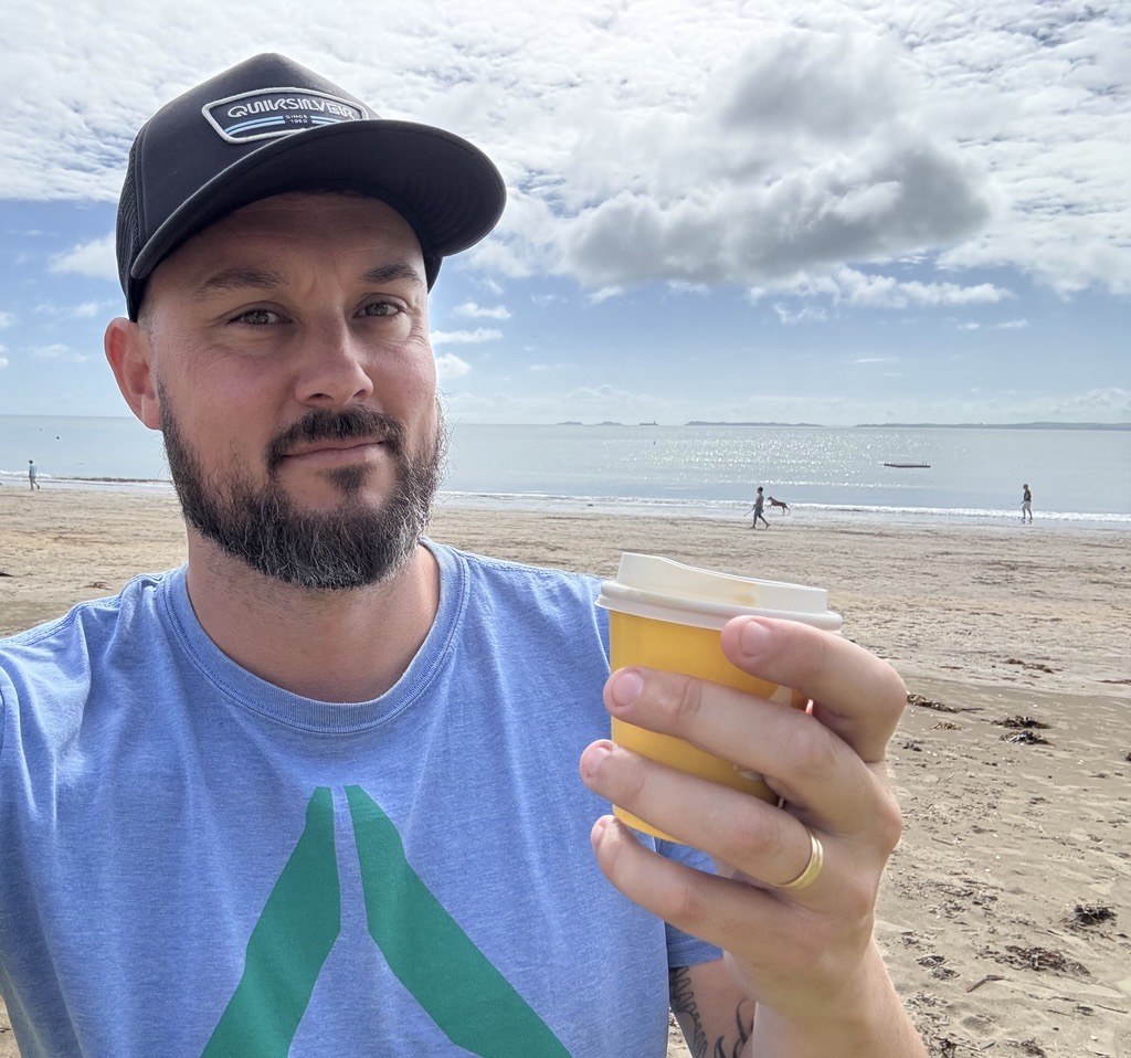 Samuel Hall enjoying a takeaway coffee by the beach